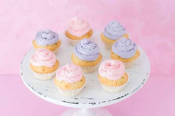 Cupcakes con crema rosa y violeta en soporte shic shabby sobre fondo pastel rosa . — Foto de Stock