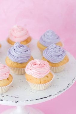 Violet ile cupcakes ve pembe krem beyaz eski püskü shic üzerinde pastel pembe arka plan