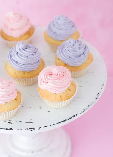 Cupcakes con crema violeta y rosa sobre blanco shabby shic stand sobre fondo rosa pastel — Foto de Stock