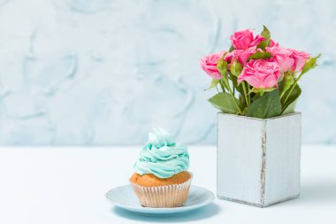 Mavi dekorasyon ve retro eski püskü şık vazoda pembe gül buketi cupcake ile mavi pastel yatay banner.