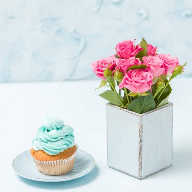 Kremalı cupcake ve pembe Gül retro shabby chic vazo içinde duran mavi pastel kare afiş ile süslenmiş.