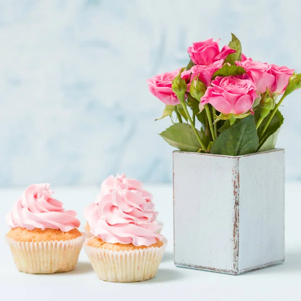 Bouquet of pink roses in retro shabby chic vase and cupcake with cream decoration. — Stock Photo, Image