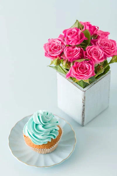 Spanduk vertikal pastel biru dengan hiasan cupcake krim biru dan mawar merah muda dalam vas chic retro lusuh . — Stok Foto