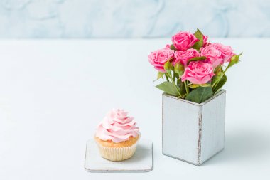 Cupcake pembe krem dekorasyon ve retro eski püskü şık vazoda gül buketi.