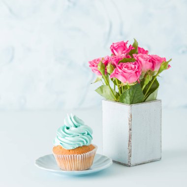 Mavi pastel kare afiş ile cupcake mavi dekorasyon ve retro eski püskü şık vazoda pembe gül buketi.