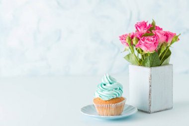 Kremalı cupcake ve retro eski püskü şık vazoda pembe Gül mavi pastel yatay afiş ile süslenmiş.