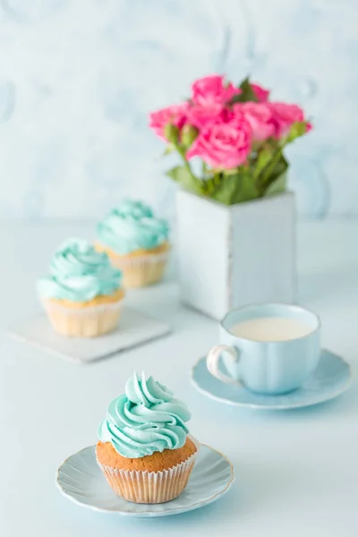 Spanduk vertikal pastel biru dengan cupcakes yang didekorasi, secangkir kopi dengan susu dan karangan mawar merah muda . — Stok Foto