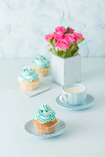 Spanduk vertikal pastel biru dengan cupcakes yang didekorasi, secangkir kopi dengan susu dan karangan mawar merah muda . — Stok Foto