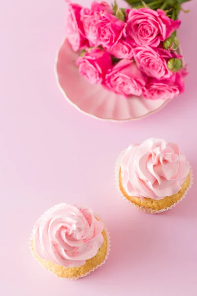 Cupcake med rosa grädde dekoration och rosor på rosa pastell bakgrund. — Stockfoto