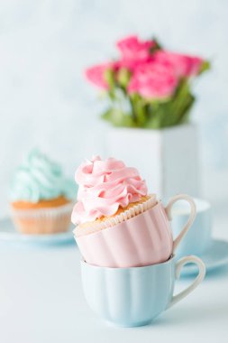 Mavi pastel afiş ile dekore edilmiş cupcakes, sütlü kahve fincan ve pembe gül buketi.