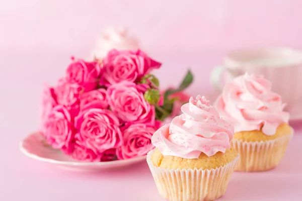 Cupcake dengan dekorasi krim merah muda dan mawar di latar belakang pastel merah muda . — Stok Foto