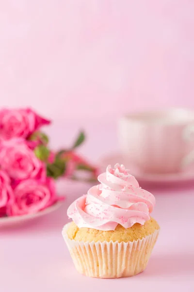 Cupcake dengan dekorasi krim merah muda dan mawar di latar belakang pastel merah muda . — Stok Foto