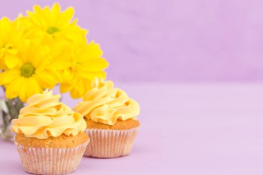 Sarı krem ve Kasımpatı Menekşe pastel arka planda tebrik kartı copyscape ile süslenmiş cupcakes.