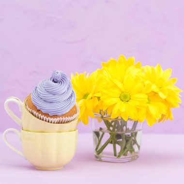 Mor krem ve metin alanı tebrik afiş için Menekşe pastel zemin üzerine sarı Kasımpatı buket cupcakes süslenmiş.