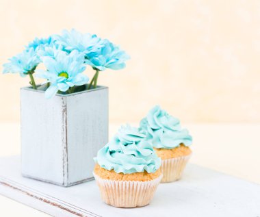 Tatlı mavi buttercream dekorasyon ve mavi krizantem retro eski püskü şık vazoda ile cupcake.