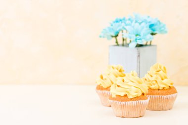 Tatlı sarı buttercream dekorasyon ve mavi krizantem retro eski püskü şık vazoda ile cupcake.
