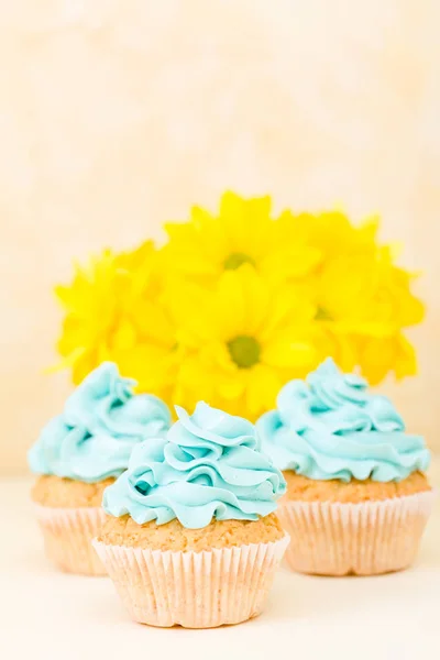 Cupcake com decoração de creme de manteiga azul doce e crisântemo amarelo em vaso chique gasto retro . — Fotografia de Stock