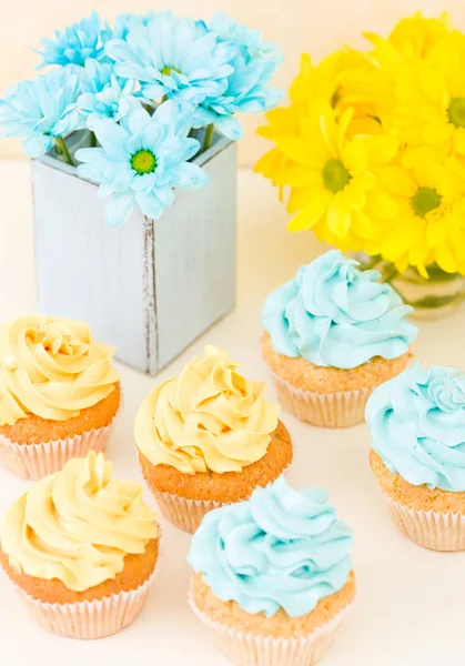 Crisântemo amarelo e azul em vaso chique gasto com cupcakes decorados com creme macio. Área de Copyscape — Fotografia de Stock