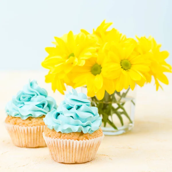 Cupcake com decoração de creme azul e buquê de crisântemo amarelo. Conceito de Copycpase — Fotografia de Stock