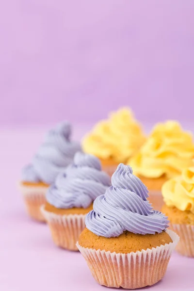 Copyscape 인사말 카드에 대 한 바이올렛 파스텔 배경에 노란색 크림 컵 케이크 장식. — 스톡 사진