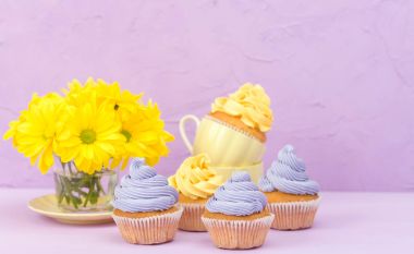 Sarı ve mor krem ve Kasımpatı Menekşe pastel arka planda tebrik kartı copyscape ile süslenmiş cupcakes.