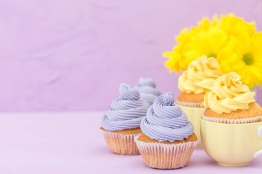 Sarı ve mor krem ve Kasımpatı Menekşe pastel arka planda tebrik kartı copyscape ile süslenmiş cupcakes.
