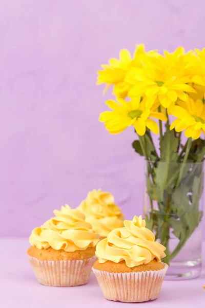 Żółta Chryzantema w szkło i ciastko z żółty krem na fioletowym tle pastel. Kwiaty i deser dzień matki układ projektowania. — Zdjęcie stockowe