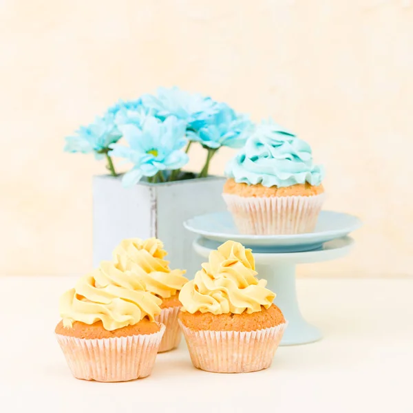 Tatlı mavi ve sarı buttercream dekorasyon ve mavi krizantem retro eski püskü şık vazoda ile cupcake. — Stok fotoğraf