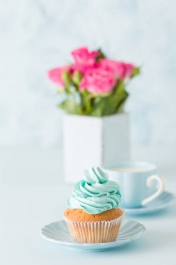 Mavi pastel dikey afiş ile dekore edilmiş cupcakes, sütlü kahve fincan ve pembe gül buketi.