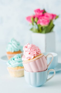Mavi pastel afiş ile dekore edilmiş cupcakes, sütlü kahve fincan ve pembe gül buketi.