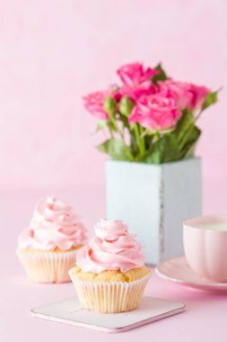 Pembe pastel dikey afiş ile dekore edilmiş cupcakes, sütlü kahve fincan ve pembe gül buketi.