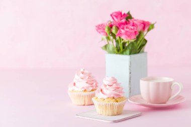 Pembe pastel yatay afiş ile dekore edilmiş cupcakes, sütlü kahve fincan ve pembe gül buketi.