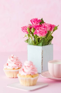 Pembe pastel dikey afiş ile dekore edilmiş cupcakes, sütlü kahve fincan ve pembe gül buketi.