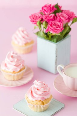 Pembe pastel dikey afiş ile dekore edilmiş cupcakes, sütlü kahve fincan ve pembe gül buketi.