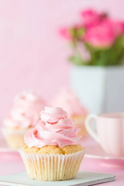 Pembe pastel dikey afiş ile dekore edilmiş cupcakes, sütlü kahve fincan ve pembe gül buketi.