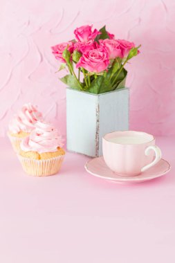 Pembe pastel dikey afiş ile dekore edilmiş cupcakes, sütlü kahve fincan ve pembe gül buketi.