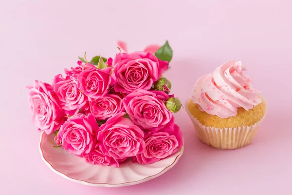 Cupcake dengan dekorasi krim merah muda dan mawar di latar belakang pastel merah muda . — Stok Foto