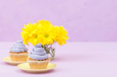 Mor krem ve metin alanı tebrik afiş için Menekşe pastel zemin üzerine sarı Kasımpatı buket cupcakes süslenmiş.