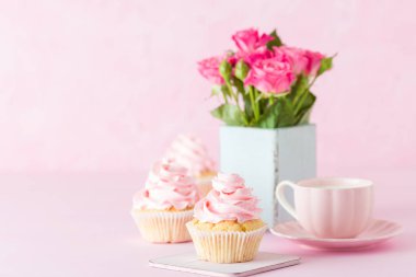 Pembe pastel yatay afiş ile dekore edilmiş cupcakes, sütlü kahve fincan ve pembe gül buketi.