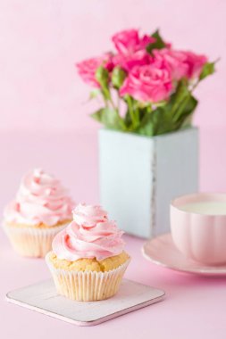 Pembe pastel dikey afiş ile dekore edilmiş cupcakes, sütlü kahve fincan ve pembe gül buketi.