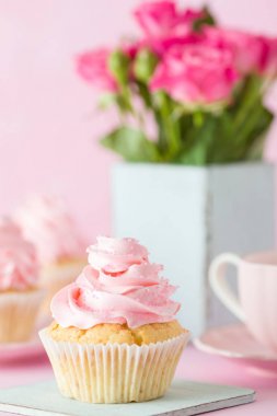 Pembe pastel dikey afiş ile dekore edilmiş cupcakes, sütlü kahve fincan ve pembe gül buketi.