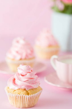 Pembe pastel dikey afiş ile dekore edilmiş cupcakes, sütlü kahve fincan ve pembe gül buketi.