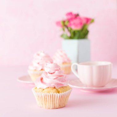 Pembe pastel afiş ile dekore edilmiş cupcakes, sütlü kahve fincan ve pembe gül buketi.