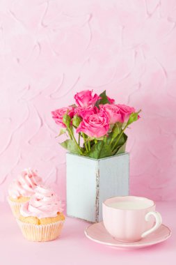 Pembe pastel dikey afiş ile dekore edilmiş cupcakes, sütlü kahve fincan ve pembe gül buketi.