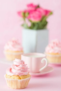 Pembe pastel dikey afiş ile dekore edilmiş cupcakes, sütlü kahve fincan ve pembe gül buketi.