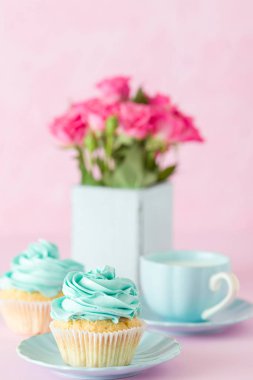 Pembe pastel dikey afiş ile dekore edilmiş cupcakes, sütlü kahve fincan ve pembe gül buketi.