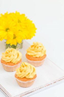 Cupcake ihale sarı krem dekorasyon ve Kasımpatı cam sarı pastel arka plan üzerinde buket.