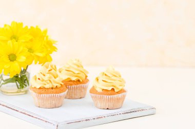 Cupcake ihale sarı krem dekorasyon ve Kasımpatı cam sarı pastel arka plan üzerinde buket.