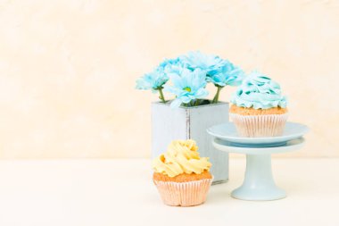 Tatlı mavi ve sarı buttercream dekorasyon ve mavi krizantem retro eski püskü şık vazoda ile cupcake.
