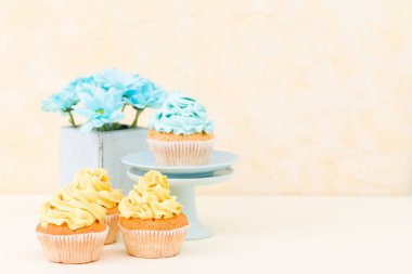 Tatlı mavi ve sarı buttercream dekorasyon ve mavi krizantem retro eski püskü şık vazoda ile cupcake.